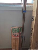 Pair of Lycor pine louvered shutters in original packaging leaning against wall