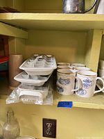 Mugs stacked with ice cube trays on shelf