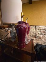 Two burgundy ginger jar lamps with shade and cords visible on side table