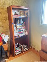 Full view of tall brown veneer bookshelf with contents