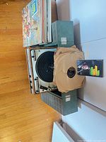 turntable centered between two green speakers with stack of LPs on side