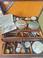 Overview showing Sherman set, enamel pill boxes, vanity boxes and assorted jewellery in open chest