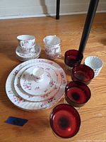 Group shot of entire lot: china plates, teacups, saucers, ruby red stem glasses, white ramekins and egg cup