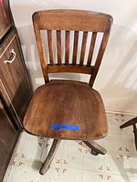 Front view of wooden swivel chair showing seat and slat back