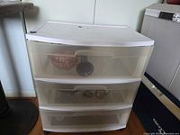 Front view of white plastic storage unit with three translucent drawers on wheels