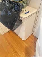 Front view of white woven plastic hamper with lid