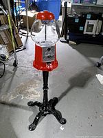 Full view of gumball machine on black pedestal stand