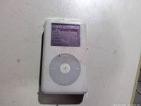 Front view of white Apple iPod showing screen and click wheel, visible dirt and wear