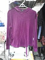 Front view of purple velour hooded top on hanger