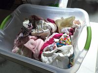 Top view of bin showing variety of baby clothes