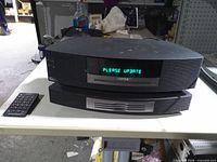 Front view showing Wave Music System III atop Multi-CD changer with display lit and remote beside