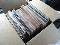 Box filled with numerous vinyl records showing edges of sleeves