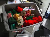 Top view of first tote showing skeins of red and green yarn, rolls of ribbon, curling ribbon spool and bows