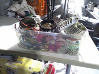 Top view of plastic bin showing variety of bangles, hair clip and feather