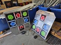 Two metal DDR GAME dance pads leaning against bins