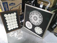 Both framed doily artworks side by side