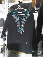 Front view of black tunic top with turquoise embroidery and ties