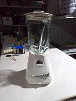 Front view showing glass jar on white base with lid