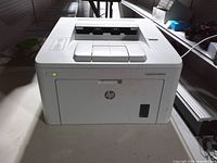 Front and side view of HP LaserJet Pro M203dw printer powered on