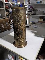 Full view of brass umbrella stand showing embossed woodland scene