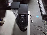 Top view of Keurig coffee maker showing control dial, display illuminated, attached power cord