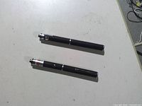 Two black pen-style laser pointers on table