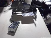 manual meat slicer on table with detached accessory