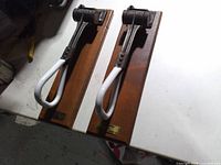 Two strap hangers mounted on wood plaques