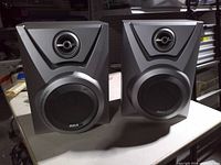 Front view of both RCA bookshelf speakers showing brand logo, tweeter, woofer grille