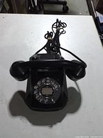 Front view of black rotary dial wall telephone with handset