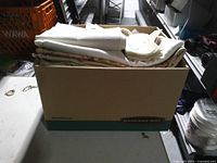 Bankers Box filled with folded white and cream linens