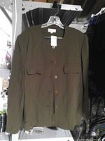 Front view of brown Tamotsu top on hanger showing button closure and pockets