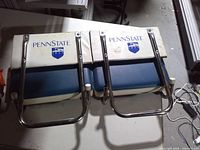 Top view of two folded Penn State stadium seats showing logos and metal frames