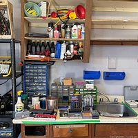 Workbench area showing drill bit sets, drawer organizers, lubricant cans and oil bottles
