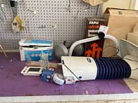 Back2Life device lying on bench with stand parts, GE bulb box, tape roll