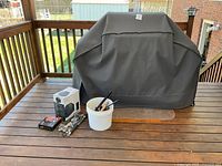 Overall lot showing covered Broil King grill and grouped accessories on deck