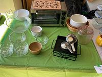 Full lot showing toaster oven, cork trivet on top, glass storage jar, ceramic casserole, measuring utensils and assorted bowls