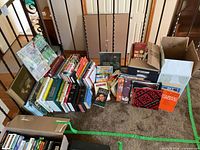 Overview of multiple stacks of assorted books on carpeted floor