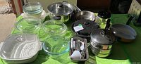 Overall lot showing glass casseroles, ceramic casserole, stainless cookware, skillets and utensils