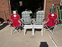 Front view of all six items: two red camp chairs, two striped lawn chairs, two white side tables
