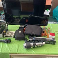 Front view of TV, set-top boxes, cases, flashlight on table