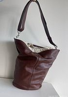 Front three-quarter view showing brown leather exterior and drawstring lining