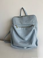 Front view of blue leather backpack purse with front zipper pocket
