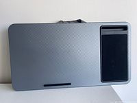 Top view showing carbon-pattern surface, mouse pad, device slot, laptop stop bar