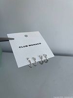 Front view of Club Monaco card with three pairs of silver hoop earrings