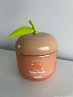 Front view of peach-shaped candle jar showing brand and scent graphics