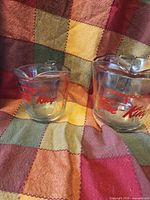 Both measuring cups front view showing Fire-King graphics and size difference