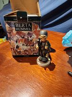 Figurine upright beside original Berta Hummel box