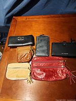 Six wallets and pouches laid out showing color and size range