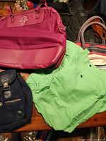 Group of magenta tote, striped tote, green linen tote, navy backpack, partial black tote visible